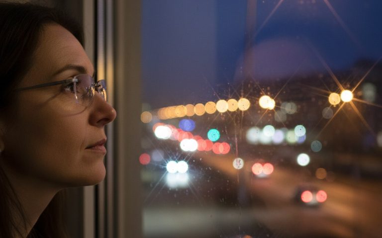 Personne avec lentilles progressives regardant une vue nocturne floue avec halos lumineux.